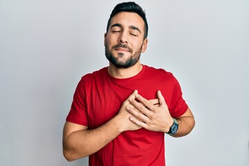 Sticker - Young hispanic man wearing casual clothes smiling with hands on chest with closed eyes and grateful gesture on face. health concept.