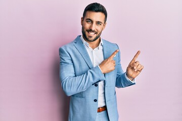 Canvas Print - Young hispanic businessman wearing business jacket smiling and looking at the camera pointing with two hands and fingers to the side.