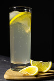Fototapeta Kuchnia - Iced tea with lemon and mint on black background. Lemonade in a glass on a dark background with lemon.