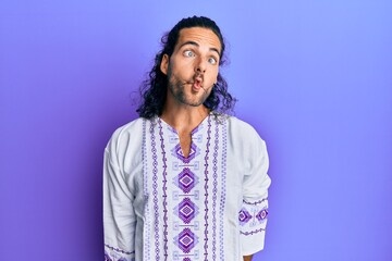 Poster - Young handsome man with long hair wearing bohemian and hippie shirt making fish face with lips, crazy and comical gesture. funny expression.