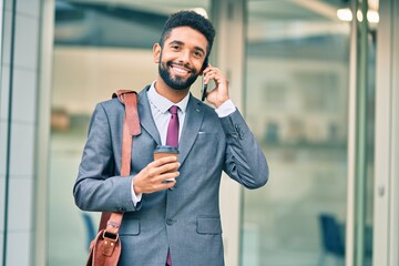 Poster - Young african american businessman talking on the smartphone and drinking take away coffee at the city.