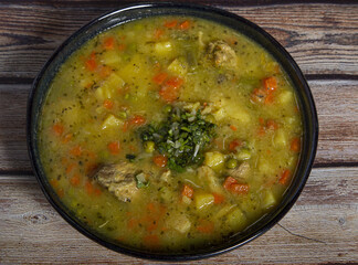 Wall Mural - High angle shot of a tasty soup made from diced tripe on a wooden tabl