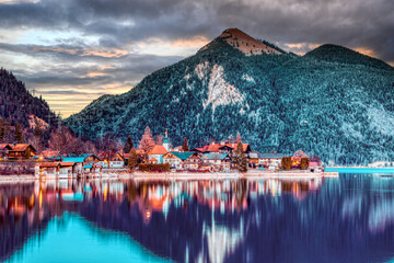 Sticker - Amazing shot of a winter scene with a small town on frozen mountain and forest background