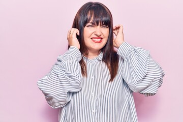 Poster - Young plus size woman wearing casual clothes covering ears with fingers with annoyed expression for the noise of loud music. deaf concept.