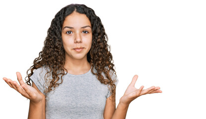 Teenager hispanic girl wearing casual clothes clueless and confused expression with arms and hands raised. doubt concept.