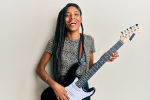 African American Woman Playing Electric Guitar Smiling And Laughing Hard Out Loud Because Funny Crazy Joke.