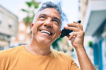 Sticker - Middle age grey-haired man smiling happy talking on the smartphone at street of city.