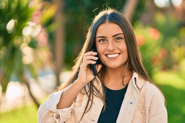 Young hispanic girl smiling happy talking on the smartphone at the park.