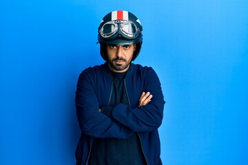 Canvas Print - Young hispanic man holding motorcycle helmet skeptic and nervous, disapproving expression on face with crossed arms. negative person.