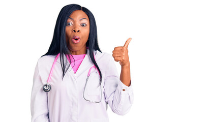 Sticker - Young african american woman wearing doctor stethoscope surprised pointing with hand finger to the side, open mouth amazed expression.