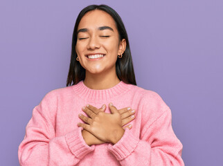 Canvas Print - Young asian woman wearing casual winter sweater smiling with hands on chest with closed eyes and grateful gesture on face. health concept.