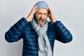 Middle age hispanic man wearing winter style with hand on head, headache because stress. suffering migraine.