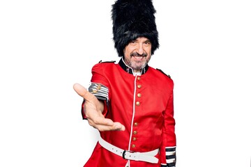 Canvas Print - Middle age handsome wales guard man wearing traditional uniform over white background smiling cheerful offering palm hand giving assistance and acceptance.