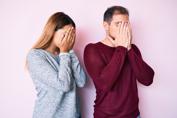 Wall Mural - Beautiful couple wearing casual clothes with sad expression covering face with hands while crying. depression concept.