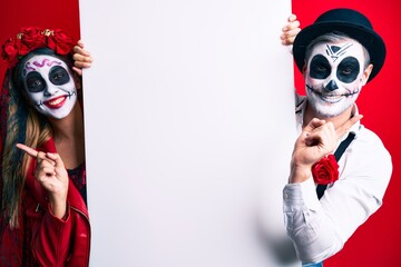 Sticker - Couple wearing day of the dead costume holding blank empty banner smiling happy pointing with hand and finger to the side