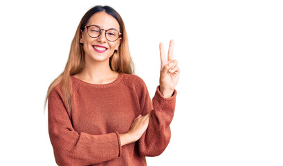 Wall Mural - Beautiful young woman wearing casual clothes and glasses smiling with happy face winking at the camera doing victory sign. number two.