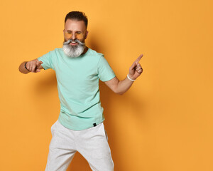 Stylish trendy gray-haired hipster guy dancing and having fun on bright orange background.