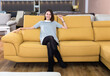 © JackF - Young attractive woman sitting on yellow sofa in furniture shop