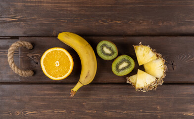 tropical fruits on a wooden background. fresh banana and kiwi. sliced orange and pineapple. dietary nutrition, the use of vitamins. healthy lifestyle. upper view, copy space