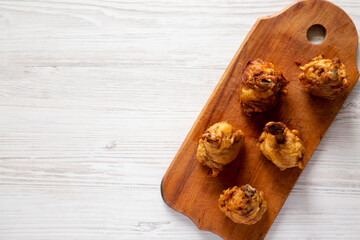 Wall Mural - Homemade Spicy Chicken Lollipop on a rustic wooden board on a white wooden surface, top view. Overhead, from above, flat lay. Space for text.