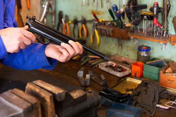 Closeup of disassembled smallbore sporting pistol in hands of gunsmith. Concept of professional repair and preventive maintenance of firearms.