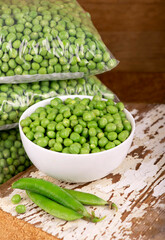 Poster - RAW baby peas in small white bowl, over retro wooden boards. Close-up.