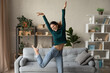 Happy young Caucasian woman have fun celebrate relocation to new home. Overjoyed millennial female renter or tenant dance in cozy own living room, moving to house. Rental, estate concept.