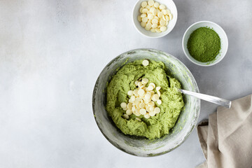 Wall Mural - baking background with green tea matcha dough in bowl, white chocolate chips, eggs, napkin. Healthy nutrition, superfoods. top view. place for your text or design.