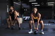 © ty - Fit and muscular couple focused on lifting a dumbbell during an exercise class in a gym.