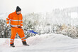 Kommunaler Service Arbeiter in oranger Sicherheitsuniform reinigt Wege und Straßen nach Schneefall