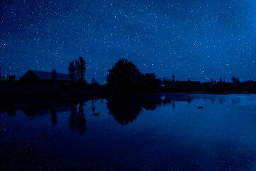 Wall Mural - milky way over a lake at summer night with clear skies under moonlight.