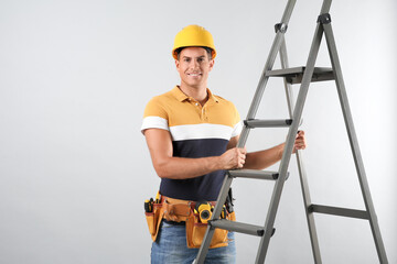 Poster - Professional builder with metal ladder on grey background