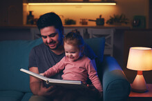 Happy Father Is Reading A Fairytale Book To Toddler Baby Girl At Home. Bedtime Story