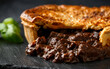 © grinchh - British beef steak pie with onion, wine gravy on rustic stone board