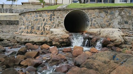 Wall Mural - salvador, bahia, brazil - january 15, 2021: pipe is seen pouring rainwater and sewage on Ondina beach in the city of Salvador. 