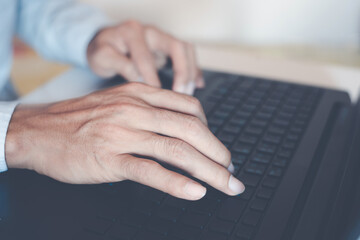 close-up of business man hand typing and using laptop keyboard for searching with technology networking on working and job on desk at work place or work at home.