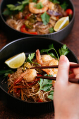 Wall Mural - Stir fried noodles with shrimps and vegetables in a wok on dark