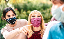 Young Multiracial People Having Fun Together Wearing Face Mask - New Normal Lifestyle Concept With Happy Friends Sharing Free Time Outside At Park - Warm Bright Filter With Focus On Middle Woman Eyes