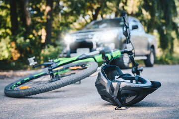 Close-up of a bicycling helmet fallen on the asphalt next to a bicycle after car accident on the road. Conceptual of accident car crash with bicycle on road.