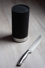 Stainless chef knife next to a knife block.