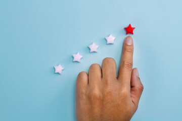 Finger pointing top rating star on blue background. Get high score rating from customer satisfaction review or top class on education concept.