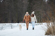 © Seventyfour - Full length portrait of happy adult couple walking together along lake in winter while enjoying nature with pet dog, copy space