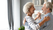 © fizkes - Happy romantic middle aged older retired family couple dancing slowly to favorite music, enjoying home dating or celebrating wedding anniversary together, showing love devotion and care, copy space.