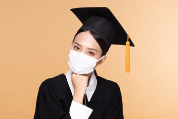 Attractive Asian woman graduated in cap and gown wear medical mask smile so proud and happiness due Virus outbrake and COVID-19 virus flu pandemic on Beige background,New normal of graduation concept