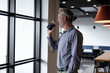 © Wavebreak Media - Caucasian businessman standing by window drinking coffee in modern office