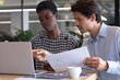© Wavebreak Media - Diverse business people sitting using laptop going through paperwork in a modern office