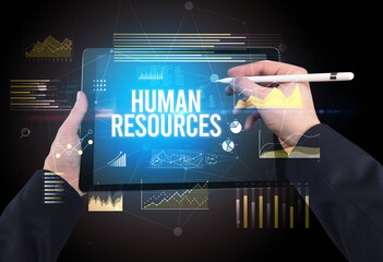 Close-up of hands holding tablet with HUMAN RESOURCES inscription, modern business concept