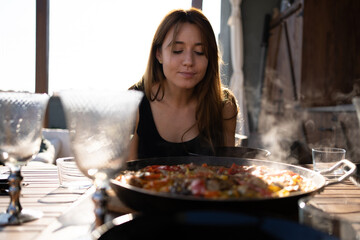 Mujer joven con paella humeante