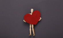 Wooden Puppet Mannequin Holding Red Heart On Gray Background