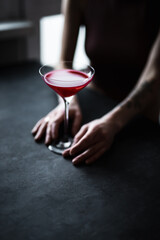 Wall Mural - A red raspberry sour cocktail in a beautiful coupe glass in girl's hands, back light, dark and moody photo